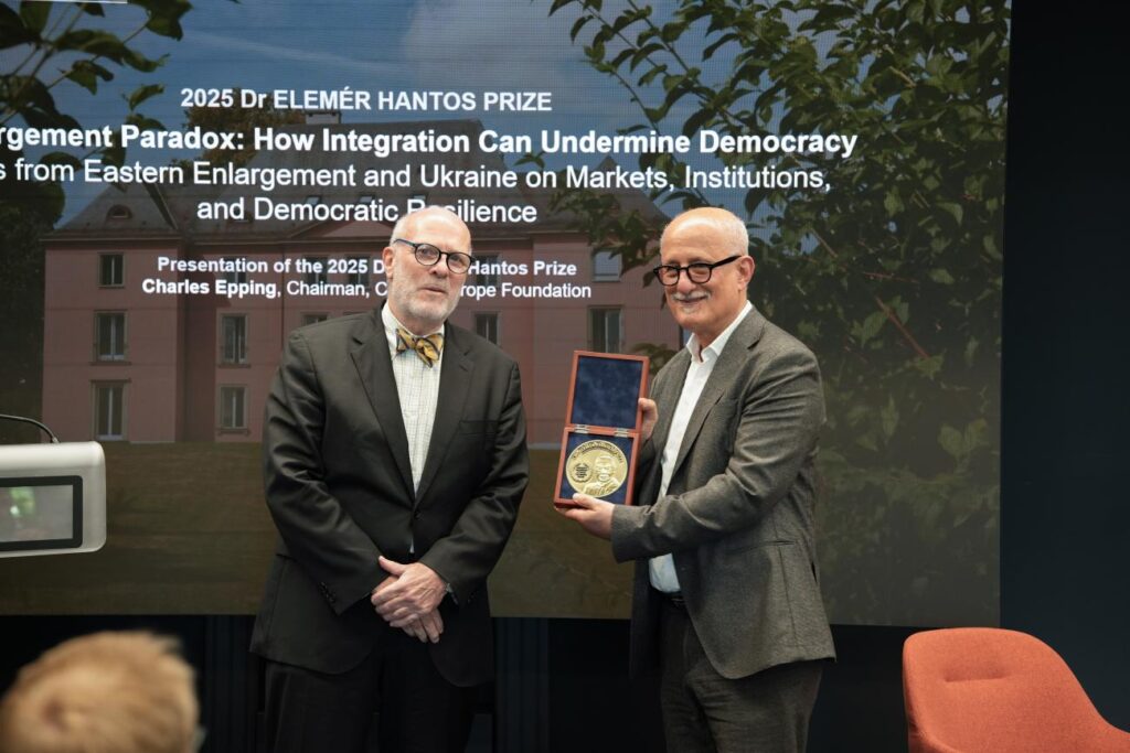 Laszlo Bruszt receiving the award, holding it up in front of him, standing next to another man